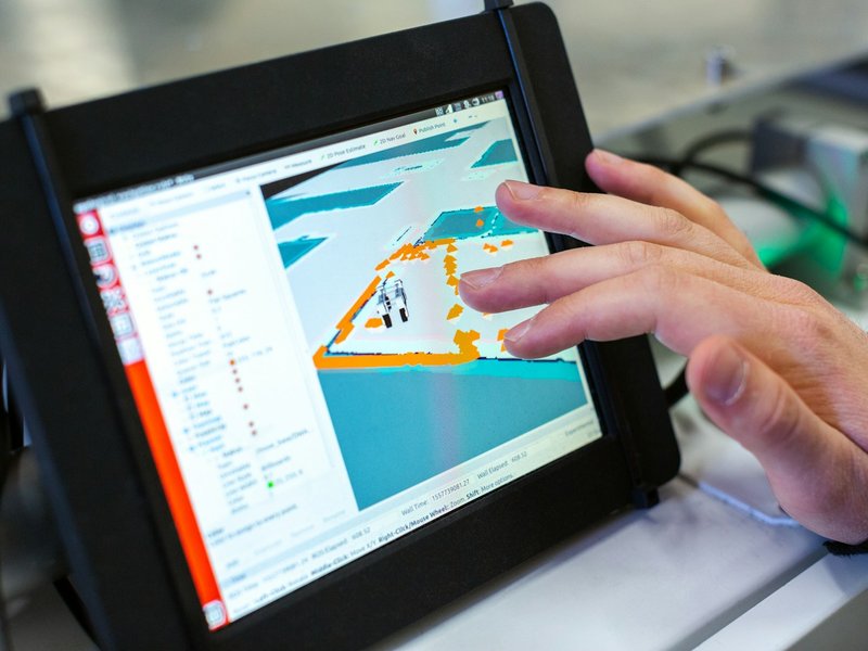 Hand touching the screen of a black ruggedized tablet