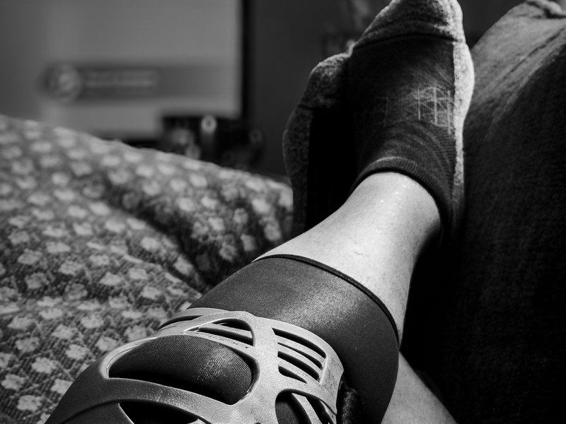 Black and white photo of a leg wearing a perforated knee brace
