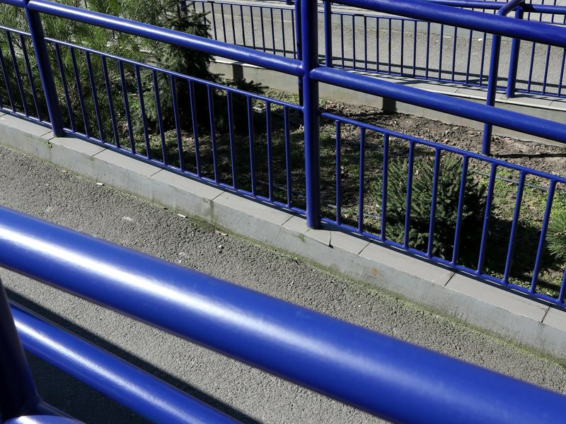 Blue metal handrails along a paved walkway