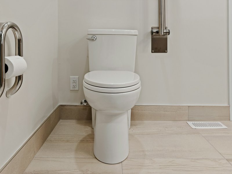 White toilet with grab bars on both sides in a bathroom