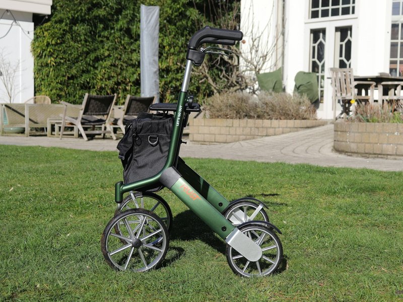 Green four-wheel rollator walker with a bag, standing on a lawn