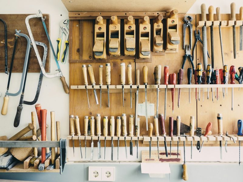 Wall rack of assorted hand tools: saws, screwdrivers, pliers and planes
