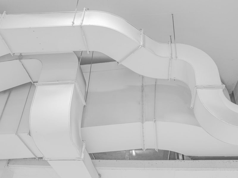 White sheet-metal ductwork running along a ceiling