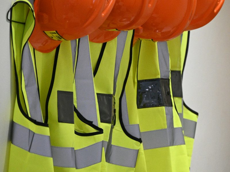 Orange hard hats and high-visibility vests hanging on a wall